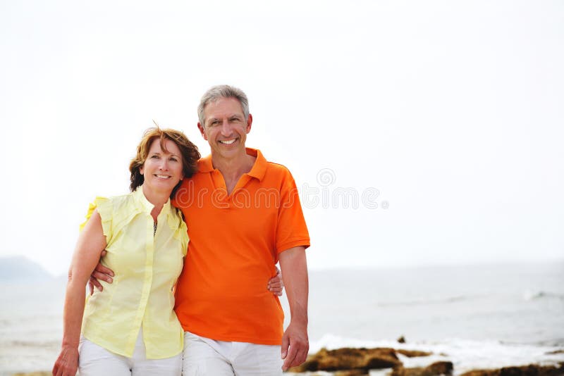 Mature couple walking along the beach. stock photography