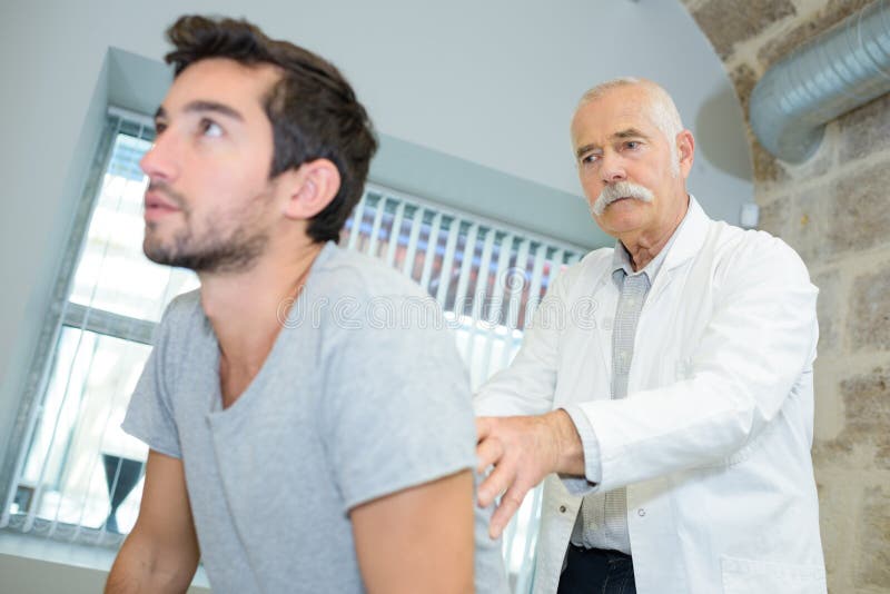 Mature doctor examining upper back young man royalty free stock photo Mature doctor examining upper back young man royalty free stock photo