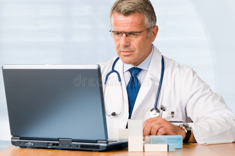 Mature doctor working on laptop stock photo