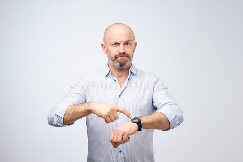 Mature european businessman impatiently pointing to his watch. Why are you late concept.