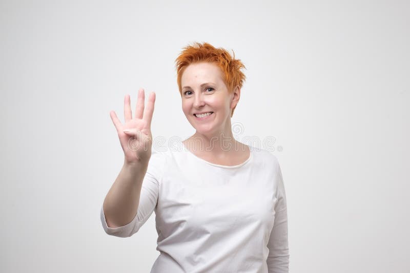Mature european woman with red hair dressed in white t-shirt showing four fingers stock photos Mature european woman with red hair dressed in white t-shirt showing four fingers stock photos