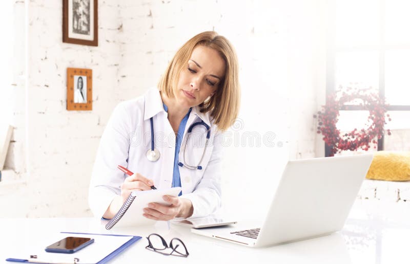Mature Female Doctor Doing Making Notes While Working In Doctor`s