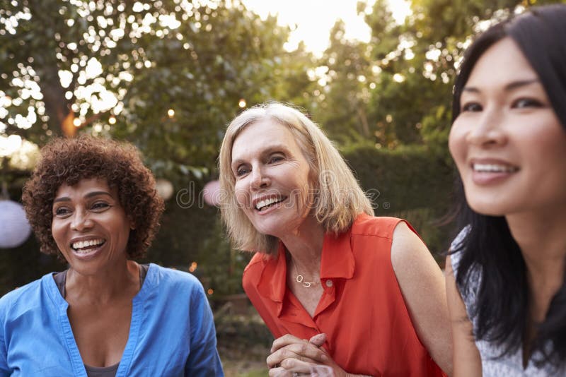 Mature Female Friends Socializing In Backyard Together