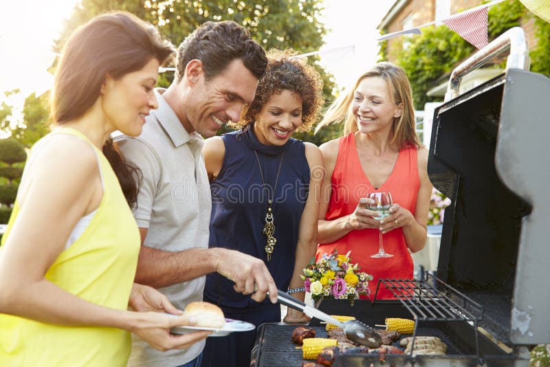 Mature Friends Enjoying Outdoor Summer Barbeque In Garden