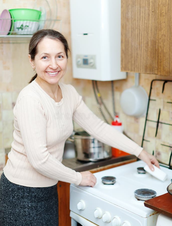 Mature Housewife Cleans The Gas-stove Stock Ph image image