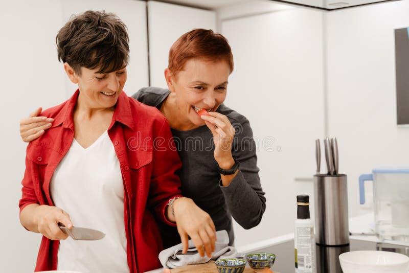 Mature Lesbian Couple Smiling While Cooking Together In Kitchen Stock Image Image Of Smiling