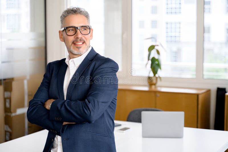 Mature male employee standing with arms crossed stock photos