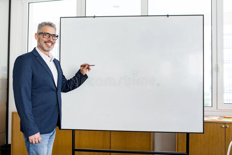 Mature male employee standing with whiteboard stock image