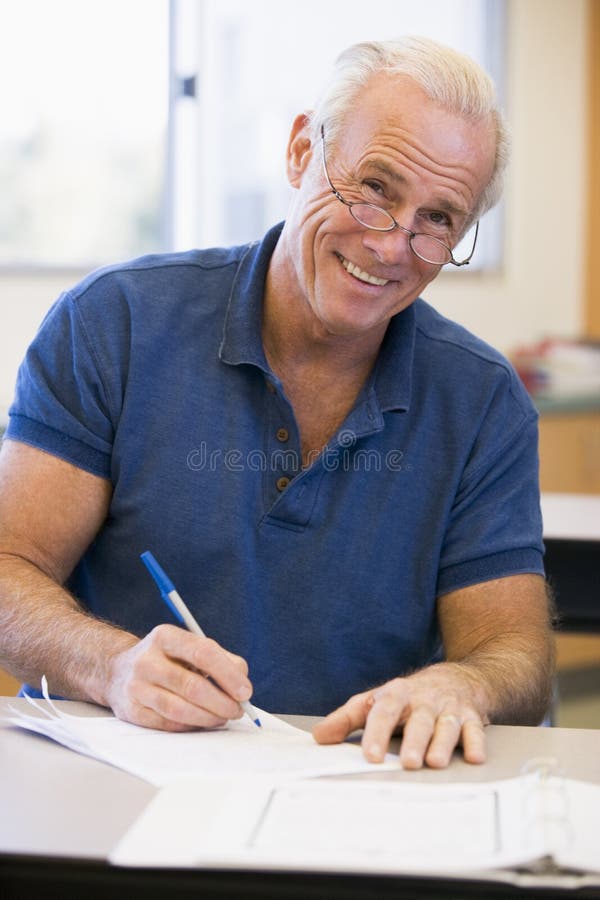 Mature male student writing in class royalty free stock photo
