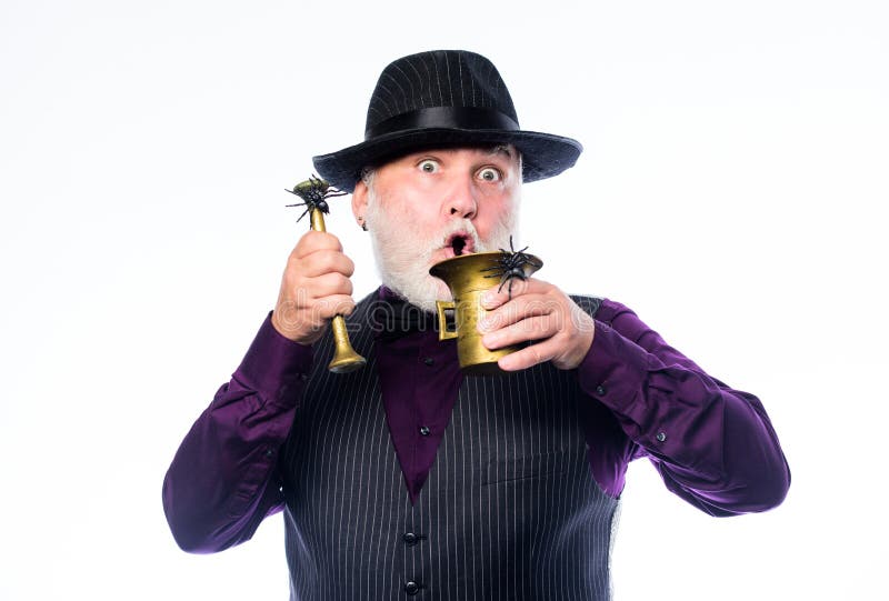 Mature man magician in witch hat. happy halloween. barman make cocktail for halloween party. evil wizard cooking magic. Potion with spider. halloween holiday stock photography Mature man magician in witch hat. happy halloween. barman make cocktail for halloween party. evil wizard cooking magic. Potion with spider. halloween holiday stock photography