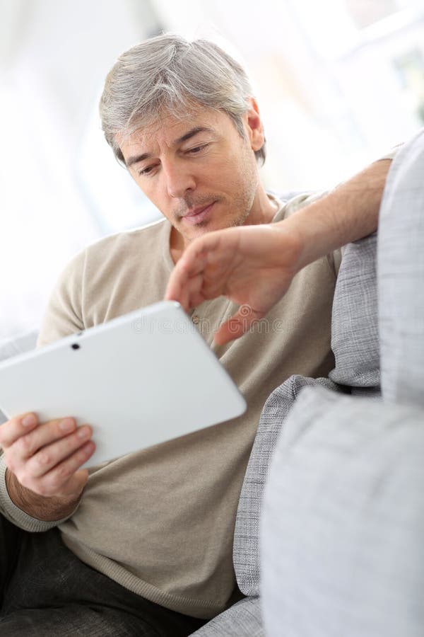 Mature man in sofa websurfing stock photo Mature man in sofa websurfing stock photo