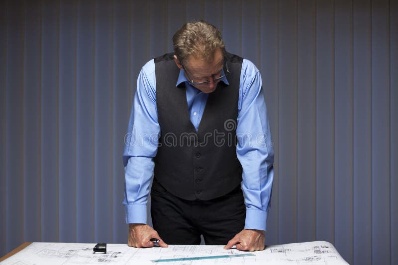 Mature manager, engineer or architect standing at a desk royalty free stock photography