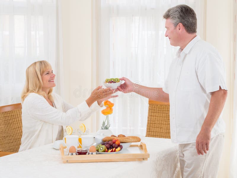 Mature senior husband serving his wife healthy breakfast