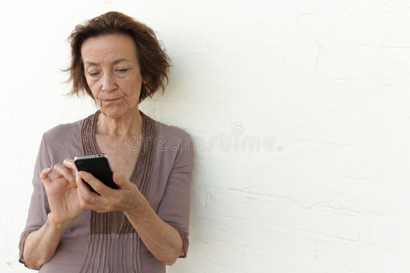 Mature woman with smartphone, annoyed while checking her social media or texting. Mature woman with smartphone, annoyed while checking her social media or texting