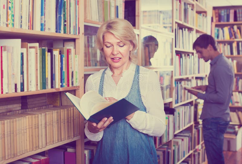 Mature Woman with Book among Bookshelves Stock Image - Image of picking