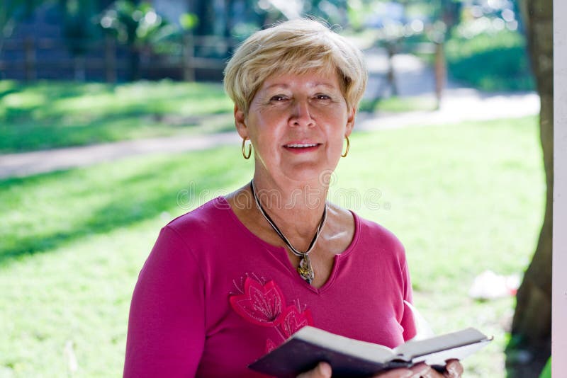 A happy elegant caucasian woman is reading a book in the sun. A happy elegant caucasian woman is reading a book in the sun.