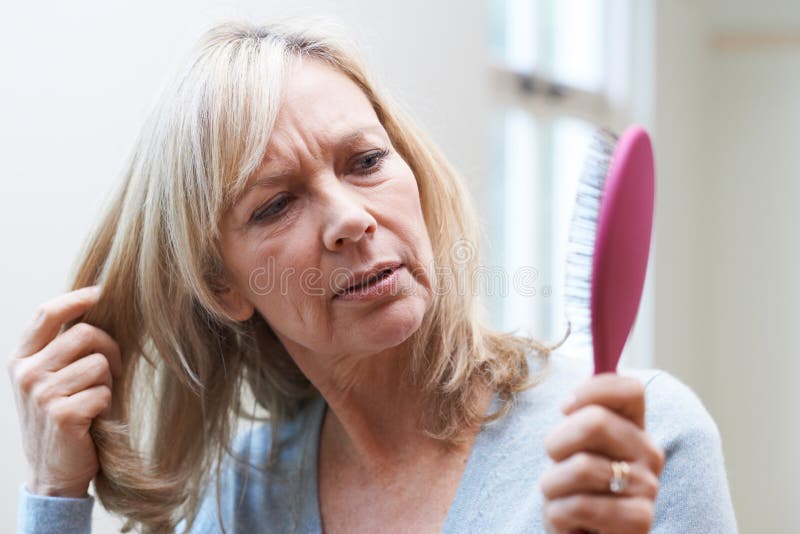 Mature Woman With Brush Concerned About Hair Loss