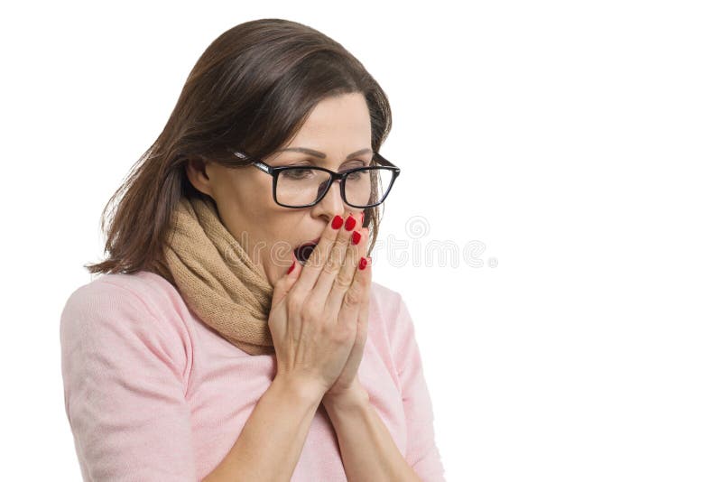 Mature woman cold, wearing a scarf warming her hands with hot breath, white background isolated.