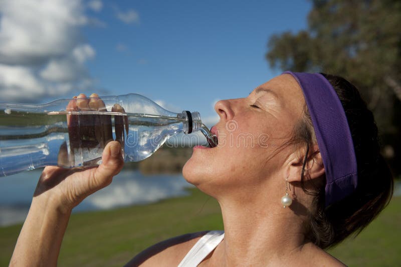 Mature Woman Drinking after Exercise. Portrait of a mature woman who is drinking out of a water bottle after exercise stock photo Mature Woman Drinking after Exercise. Portrait of a mature woman who is drinking out of a water bottle after exercise stock photo