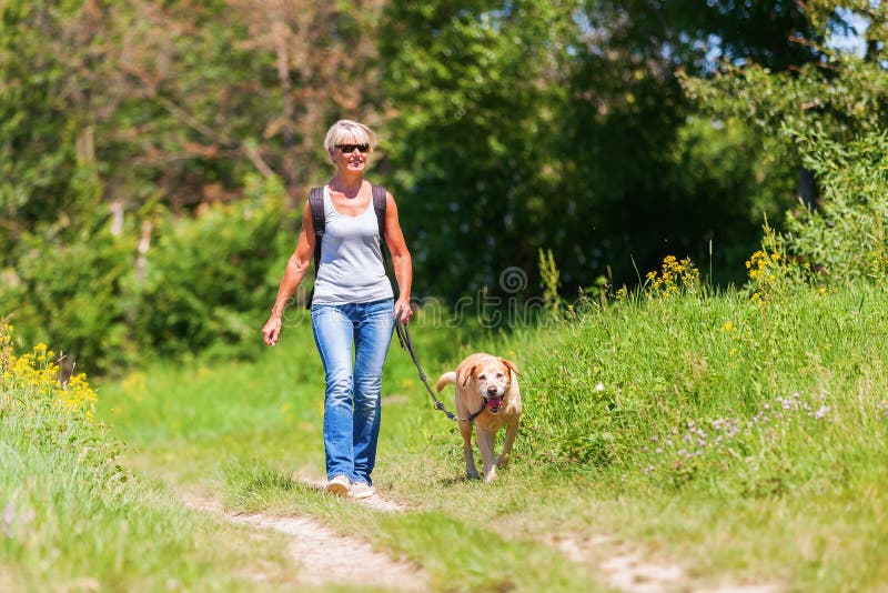 Mature woman hiking with dog in the landscape stock photo