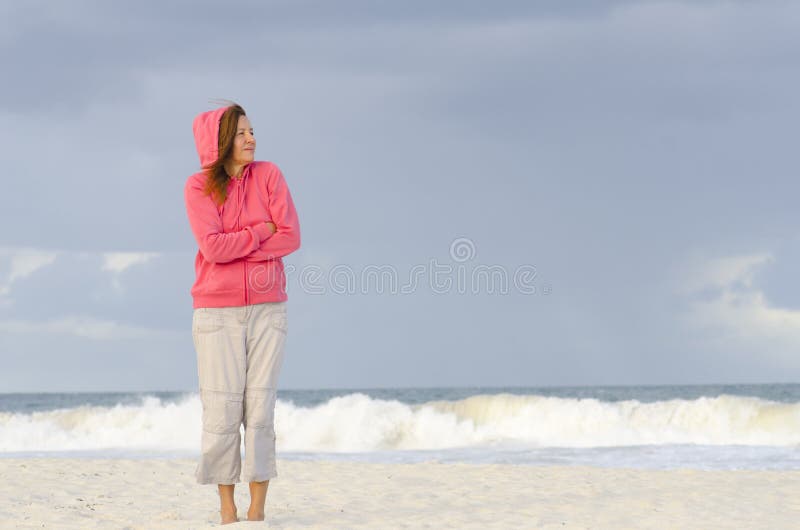 Mature woman keeping warm at beach