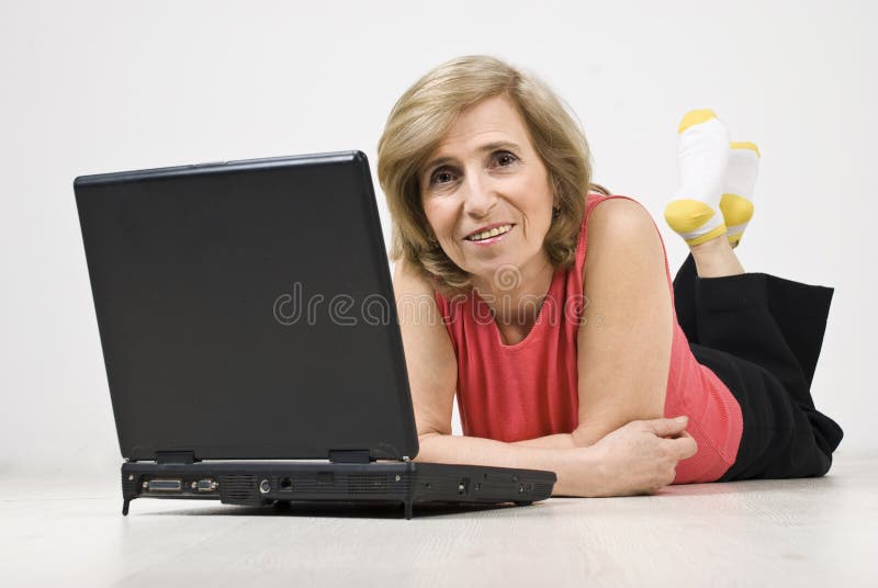 Mature woman lying on floor using laptop