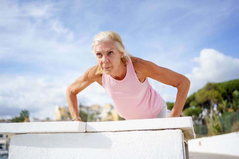 Mature Woman Working Strength Training Push Ups Against Sky with ...