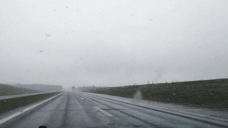 Mauvaises conditions de conduite sur une autoroute dans la neige mouillée et le temps pluvieux. vue avant de la voiture floue. mas banque de vidéos