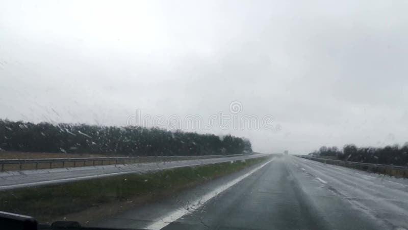 Mauvaises conditions de conduite sur une autoroute dans la neige mouillée et le temps pluvieux. vue avant de la voiture floue. mas banque de vidéos