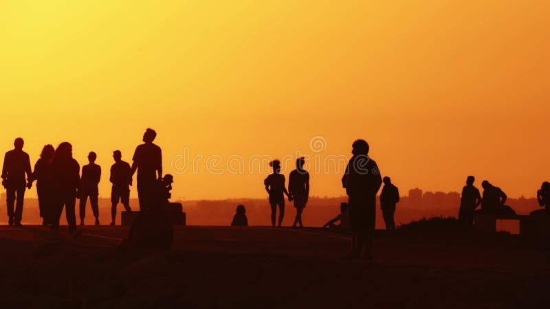 24 may 2023, Costa da Caparica, Portugal: Black silhouettes of young people on the hill at sunset