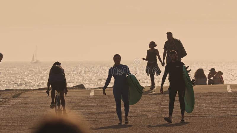 24 may 2023, Costa da Caparica, Portugal - People with surfboard walking near ocean at sunset