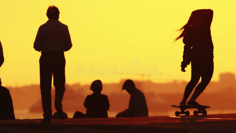 24 may 2023, Costa da Caparica, Portugal: silhouette of a woman skating on a skateboard at bright sunset