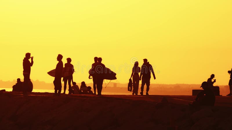 24 may 2023, Costa da Caparica, Portugal: silhouettes of young people holding surfboards on the hill at sunset