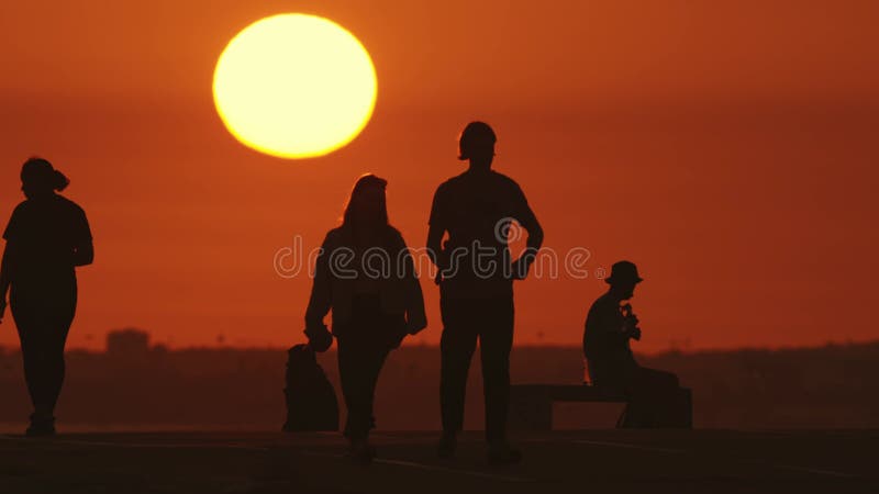 24 may 2023, Costa da Caparica, Portugal: silhouettes of youth at orange sunset - a man playing guitar