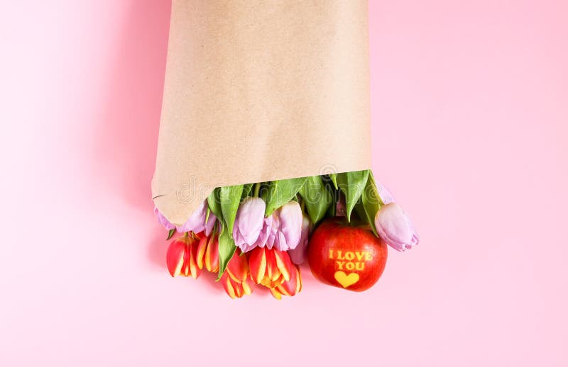 Mazzo dei fiori del tulipano della molla avvolti nel sacco di carta del mestiere su fondo rosa molle fotografia stock Mazzo dei fiori del tulipano della molla avvolti nel sacco di carta del mestiere su fondo rosa molle fotografia stock