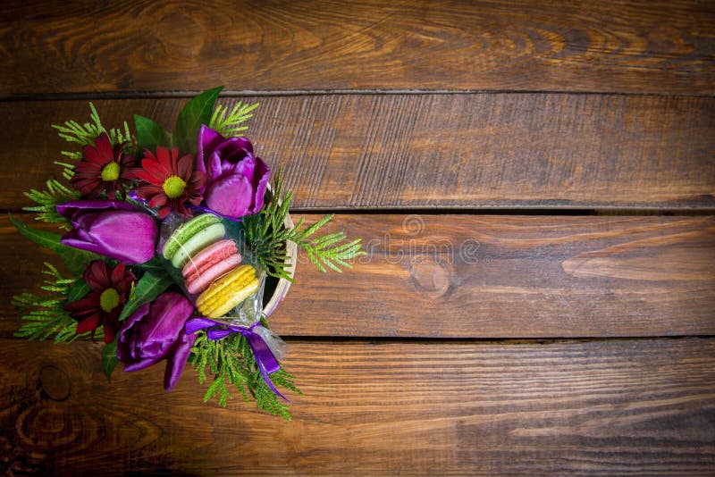Mazzo dei fiori e dei biscotti in vaso da fiori su una tavola di legno fotografia stock libera da diritti Mazzo dei fiori e dei biscotti in vaso da fiori su una tavola di legno fotografia stock libera da diritti