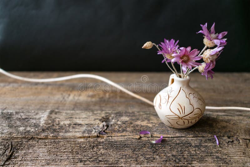 Mazzo dei pochi fiore lilla Xeranthemum sul vaso rotondo dell'argilla sul wo fotografie stock Mazzo dei pochi fiore lilla Xeranthemum sul vaso rotondo dell'argilla sul wo fotografie stock