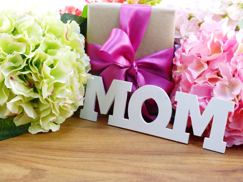 Mazzo di fiori artificiali con un contenitore di regalo e una mamma di parola su fondo di legno fotografie stock Mazzo di fiori artificiali con un contenitore di regalo e una mamma di parola su fondo di legno fotografie stock