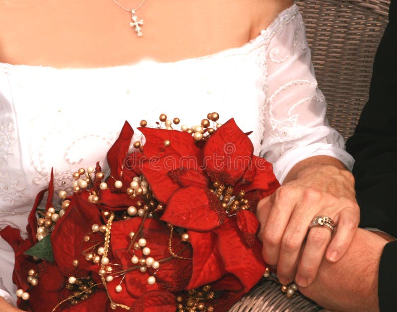 Bridal bouquet of red poinsettias, showing white wedding gown, bride and groom holding hands, with her ring and cross. Bridal bouquet of red poinsettias, showing white wedding gown, bride and groom holding hands, with her ring and cross