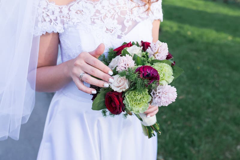 Mazzo variopinto di belle nozze in mani della sposa Fiori d'avanguardia e moderni di nozze Una fede nuziale sul dito della b immagine stock Mazzo variopinto di belle nozze in mani della sposa Fiori d'avanguardia e moderni di nozze Una fede nuziale sul dito della b immagine stock