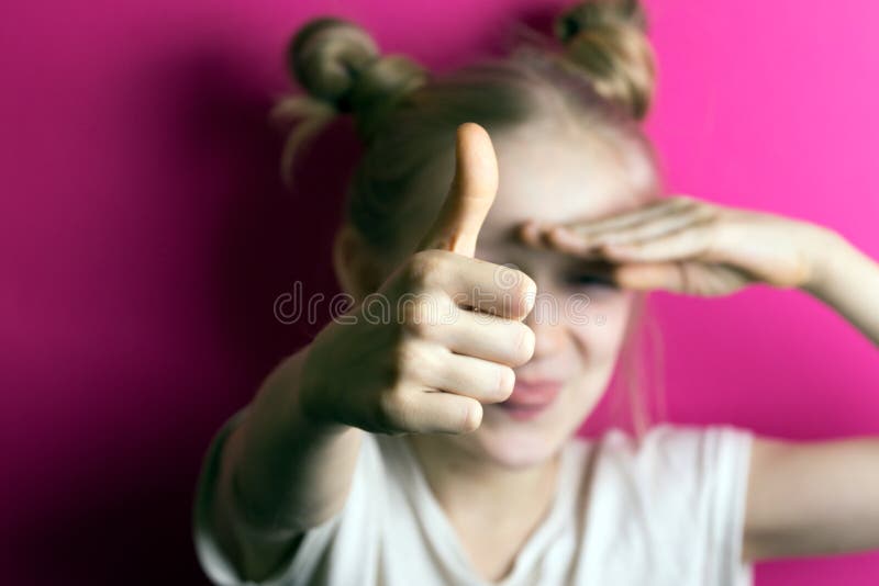 Małej dziewczynki blondynka na różowym tle. Mała piękna dziewczyny blondynka na różowym tle Szczęśliwa dziecko dziewczyna z dużym kciukiem w górę robić ok znakowi