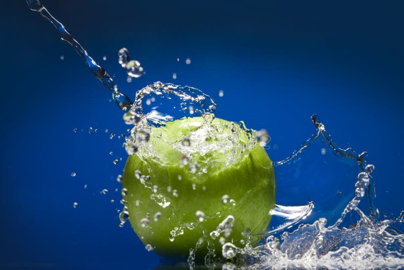 Maçã verde com respingo da água no azul imagem de stock Maçã verde com respingo da água no azul imagem de stock