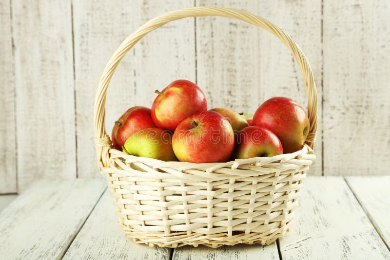 Maçãs bonitas na cesta no fundo de madeira branco fotografia de stock royalty free