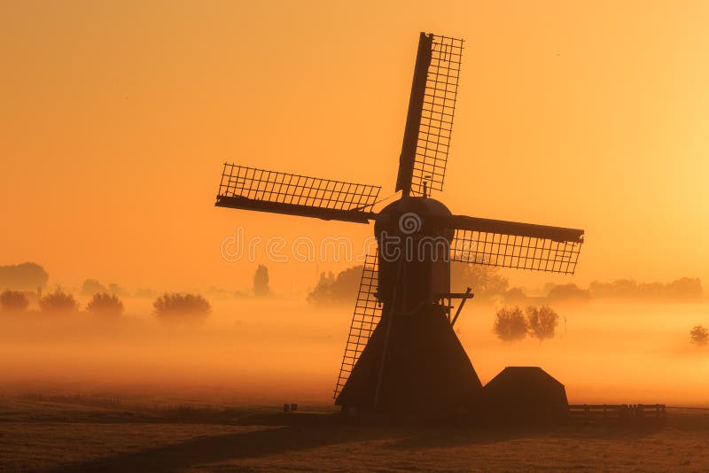 Beautiful silhouette of a traditional windmill on a foggy morning in the Netherlands. Beautiful silhouette of a traditional windmill on a foggy morning in the Netherlands