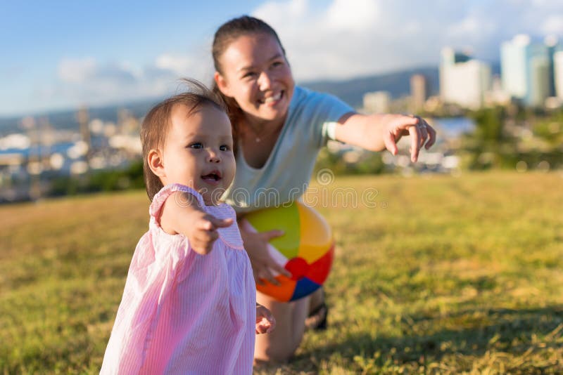 Mała dziewczynka i jej matka learing bawić się balowe gry w ładnym popołudniu przy parkiem fotografia stock Mała dziewczynka i jej matka learing bawić się balowe gry w ładnym popołudniu przy parkiem fotografia stock