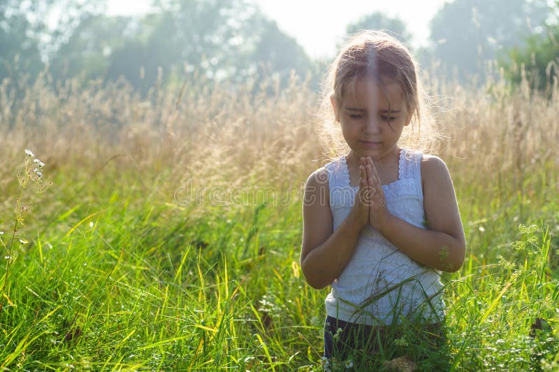 Little girl closed her eyes, praying outdoors, Hands folded in prayer concept for faith, spirituality and religion. Peace, hope, dreams concept. Little girl closed her eyes, praying outdoors, Hands folded in prayer concept for faith, spirituality and religion. Peace, hope, dreams concept.