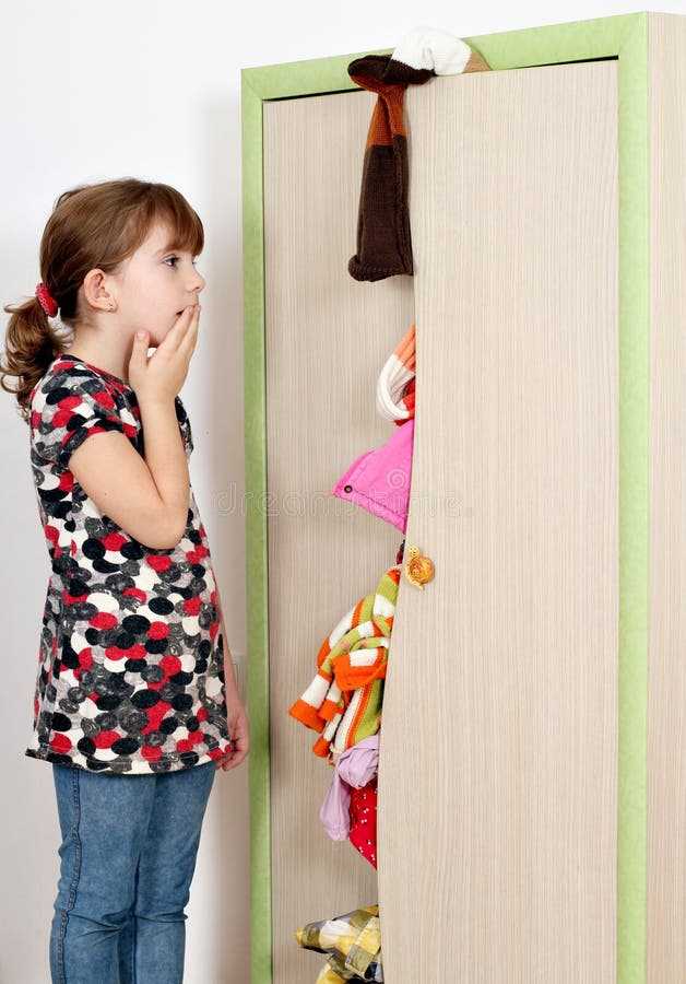 Shocked little girl looking into a messy closet. Shocked little girl looking into a messy closet