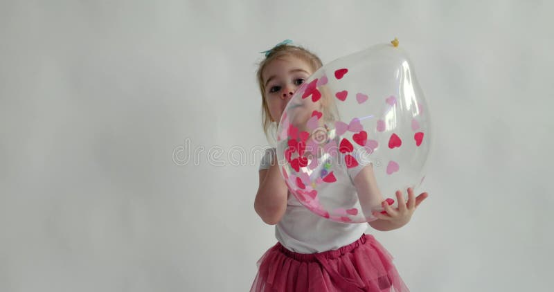 Mała 2-letnia dziewczynka bawiąca się balonem z papierami o kształcie serca