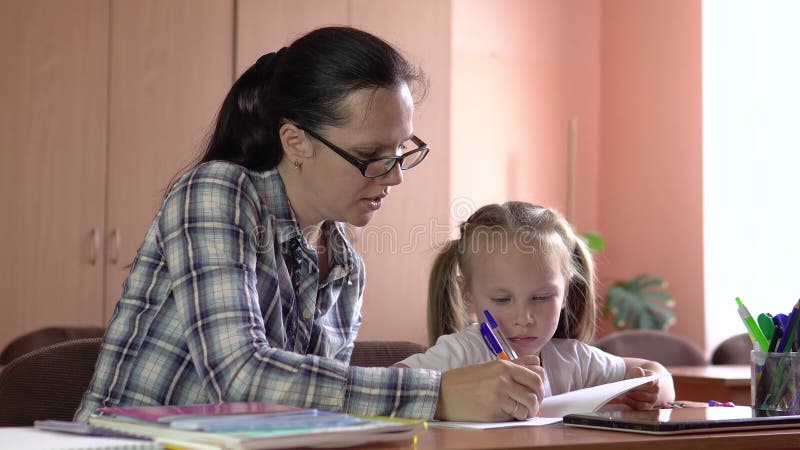 Mała piękna dziewczyna jest zaręczona z nauczycielem w szkole. rysuje notes za pomocą pióra. przedszkola