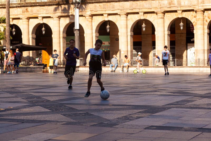 Bilbao, Spain - August 02, 2022: : Little kids playing football together in the Bilbao square at summertime. Bilbao, Spain - August 02, 2022: : Little kids playing football together in the Bilbao square at summertime